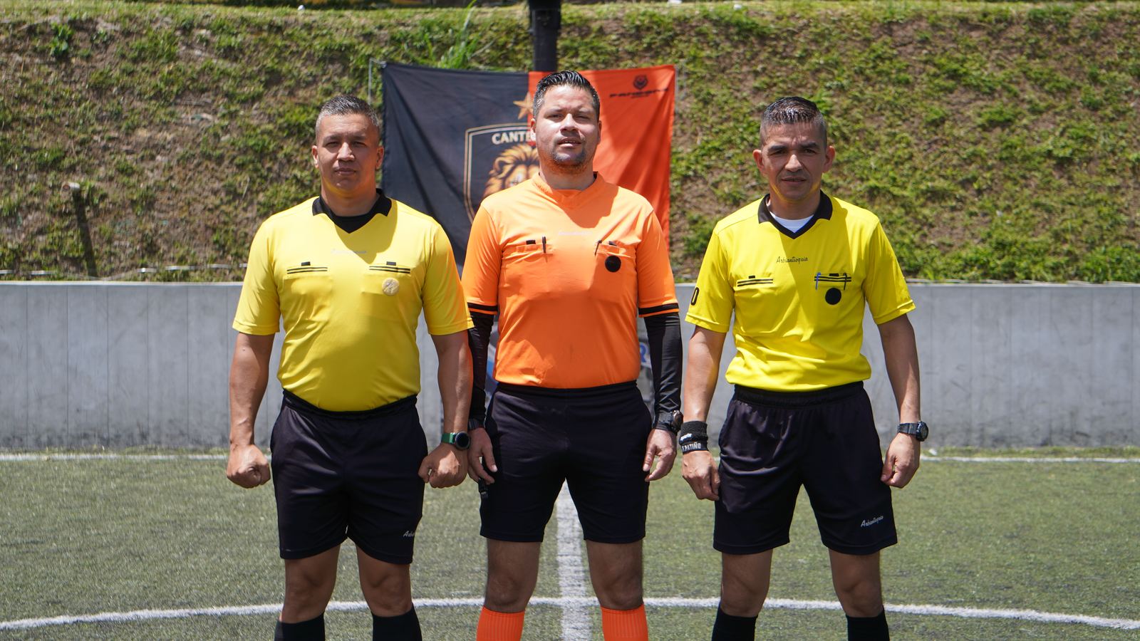 Torneo Relámpago Cantera FC — trío arbitral posando frente al banner de Cantera FC